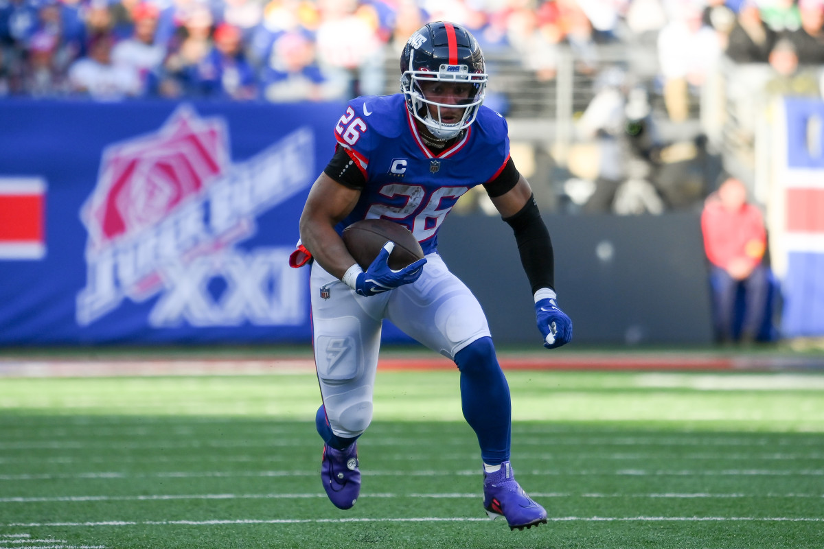 New York Giants running back Saquon Barkley looks down as he runs with the ball in one hand